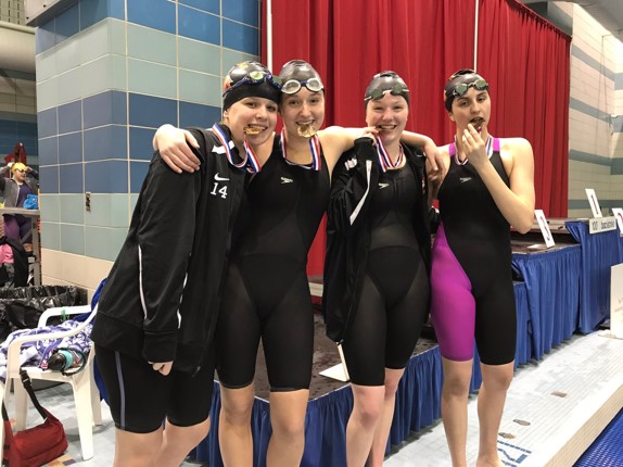 female swimmers biting medals